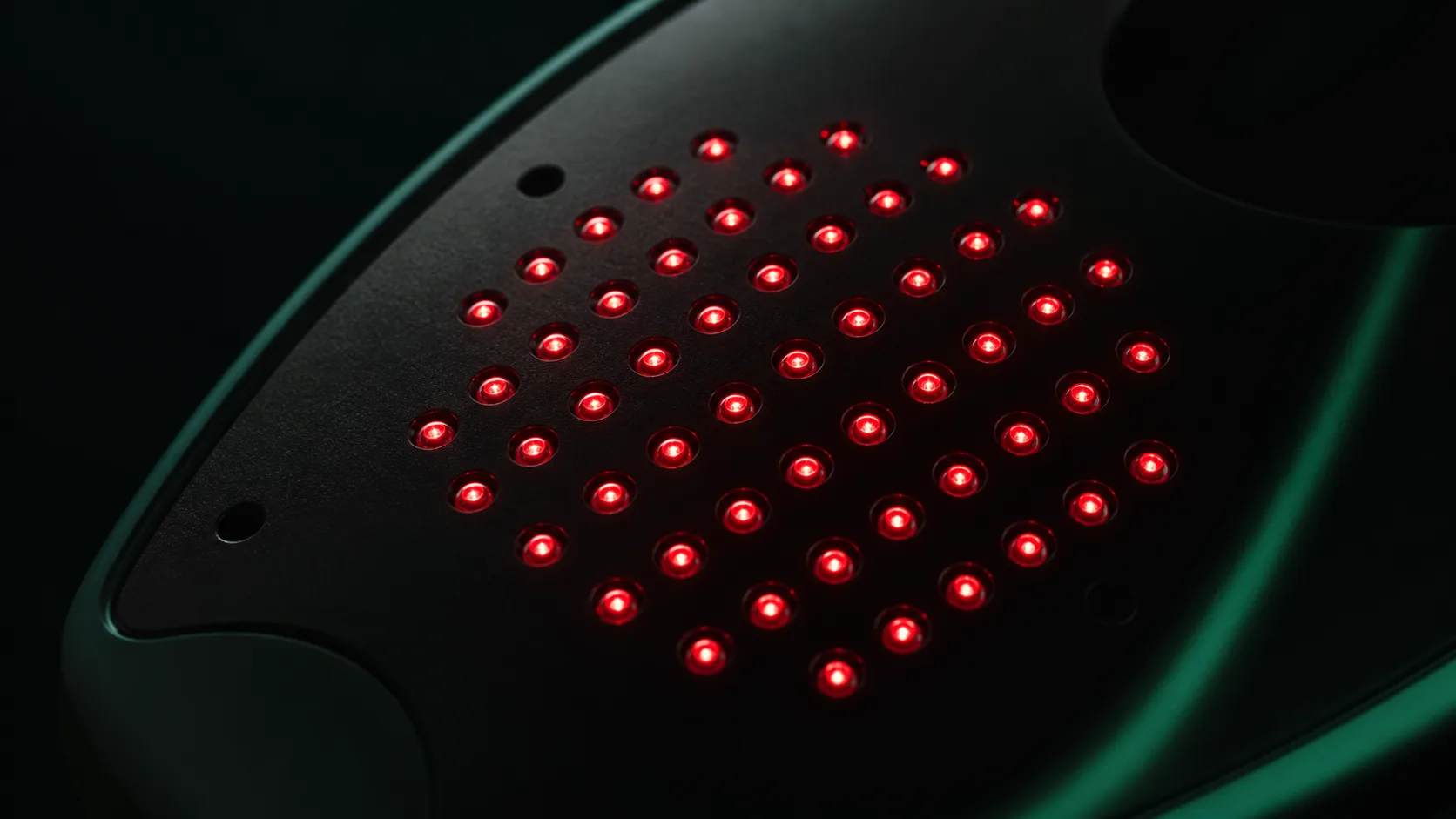 Macro photograph of a dense array of red laser diodes glowing inside a hair-growth device
